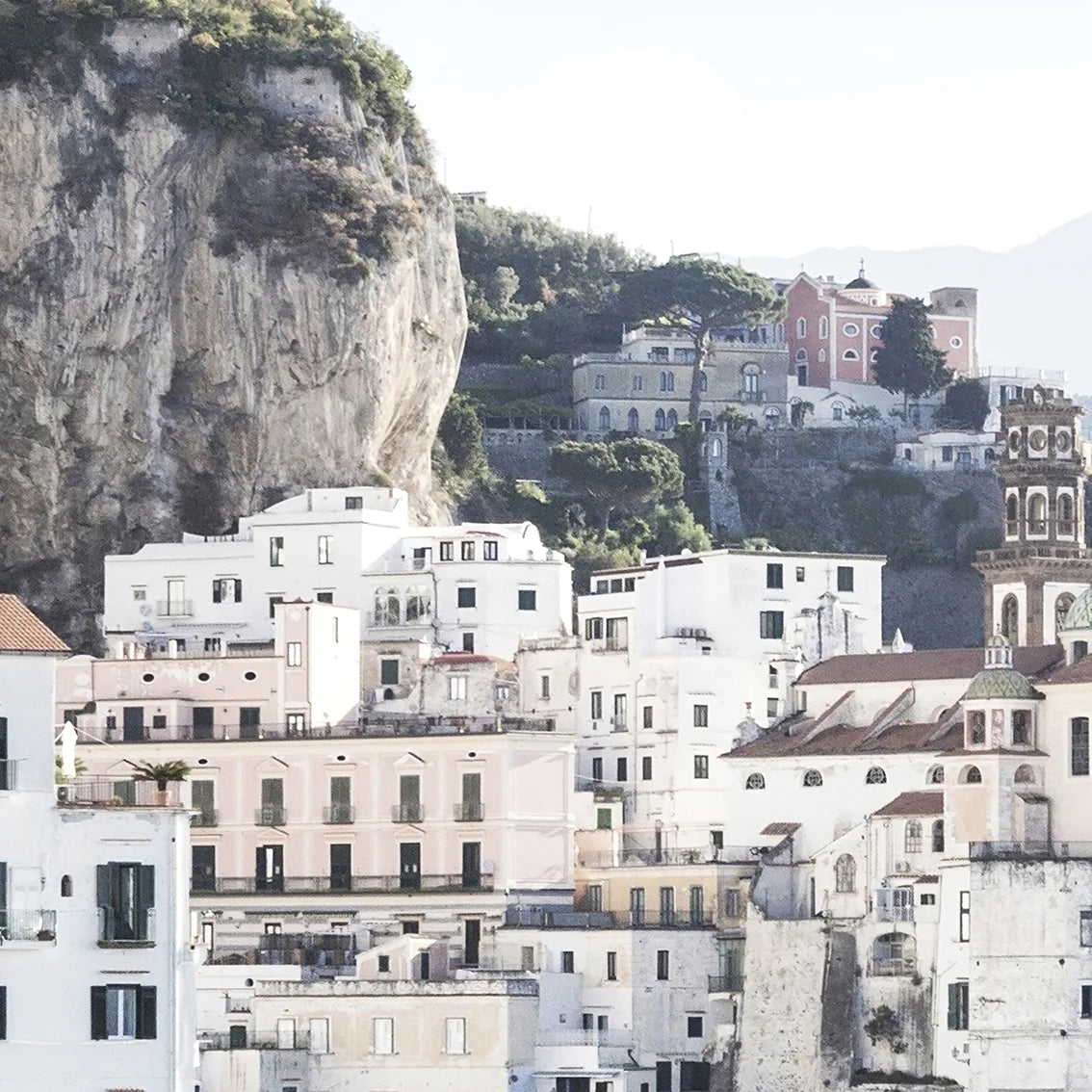 Wall art of a Mediterranean coastal town with historic white buildings and sea arches in daylight