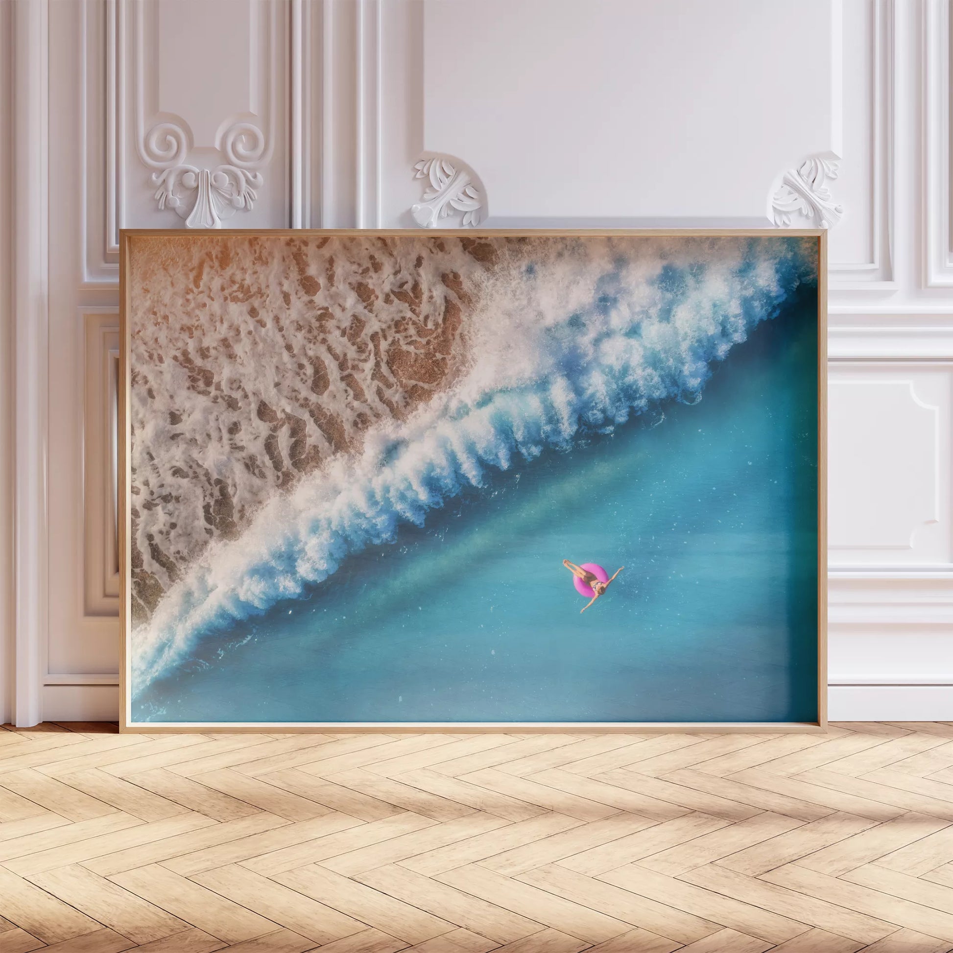 ターコイズブルーの海と波しぶき、ピンクの浮き輪のある空撮アート