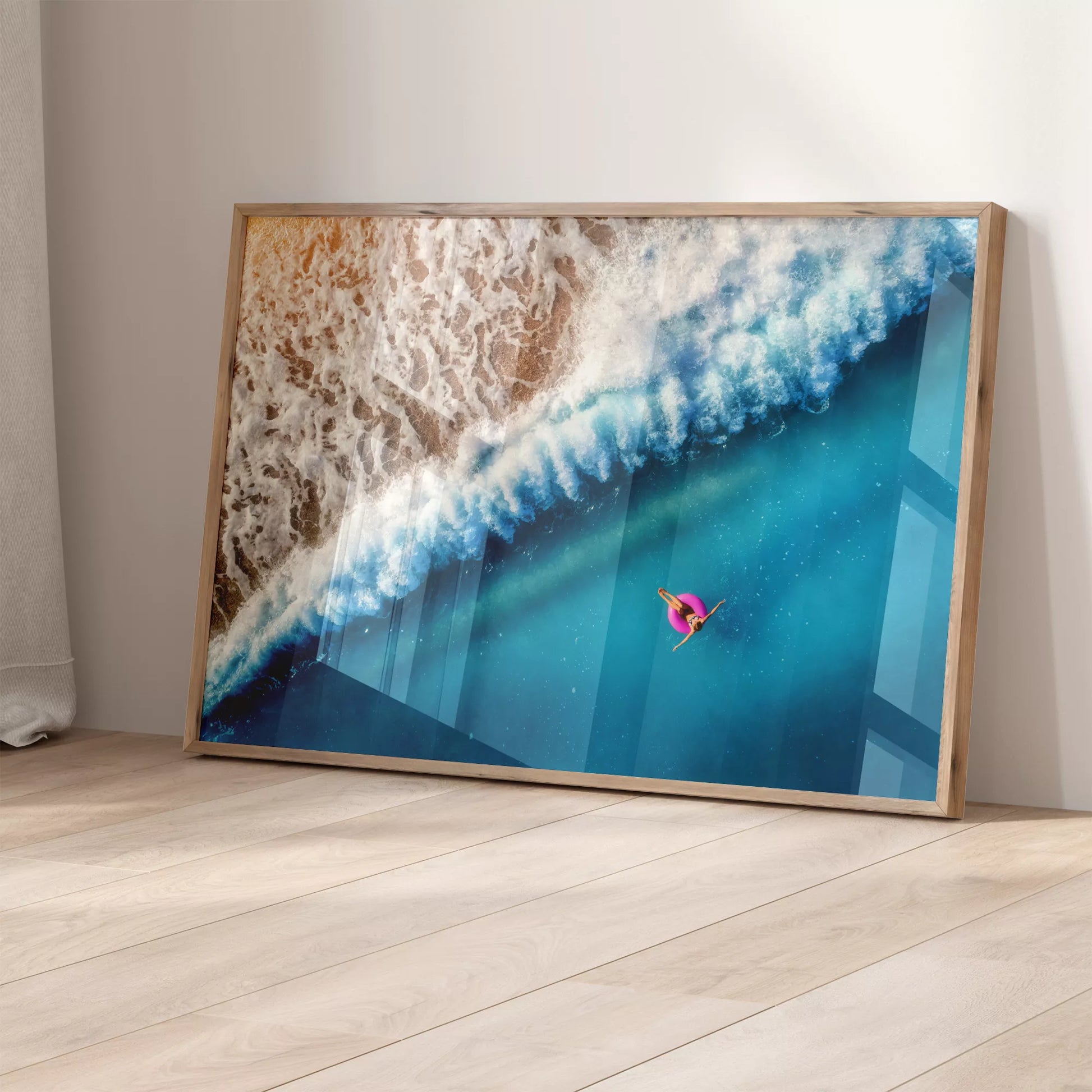 ターコイズブルーの海と波しぶき、ピンクの浮き輪のある空撮アート