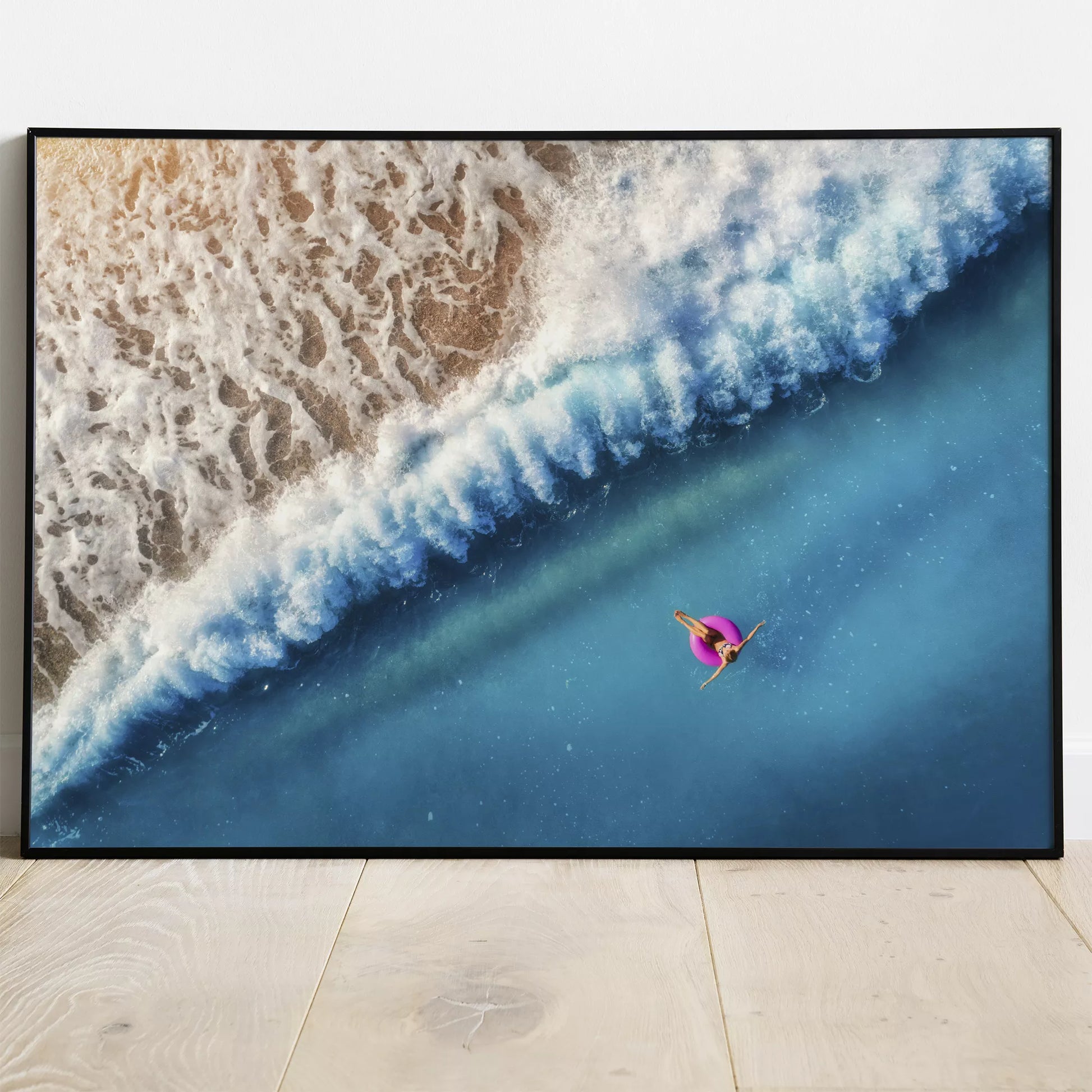 ターコイズブルーの海と波しぶき、ピンクの浮き輪のある空撮アート