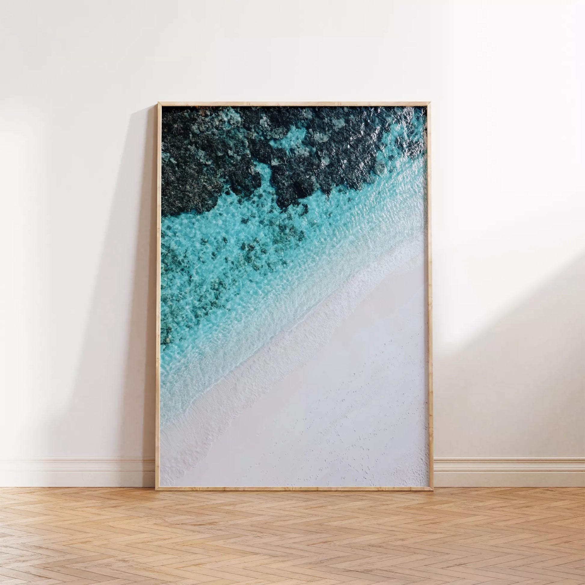 空撮で撮影された白い砂浜とターコイズブルーの海が織りなす美しいグラデーション。深い青から透明な水へと変化する海の色彩と、真っ白な砂浜のコントラストが印象的なアート写真。