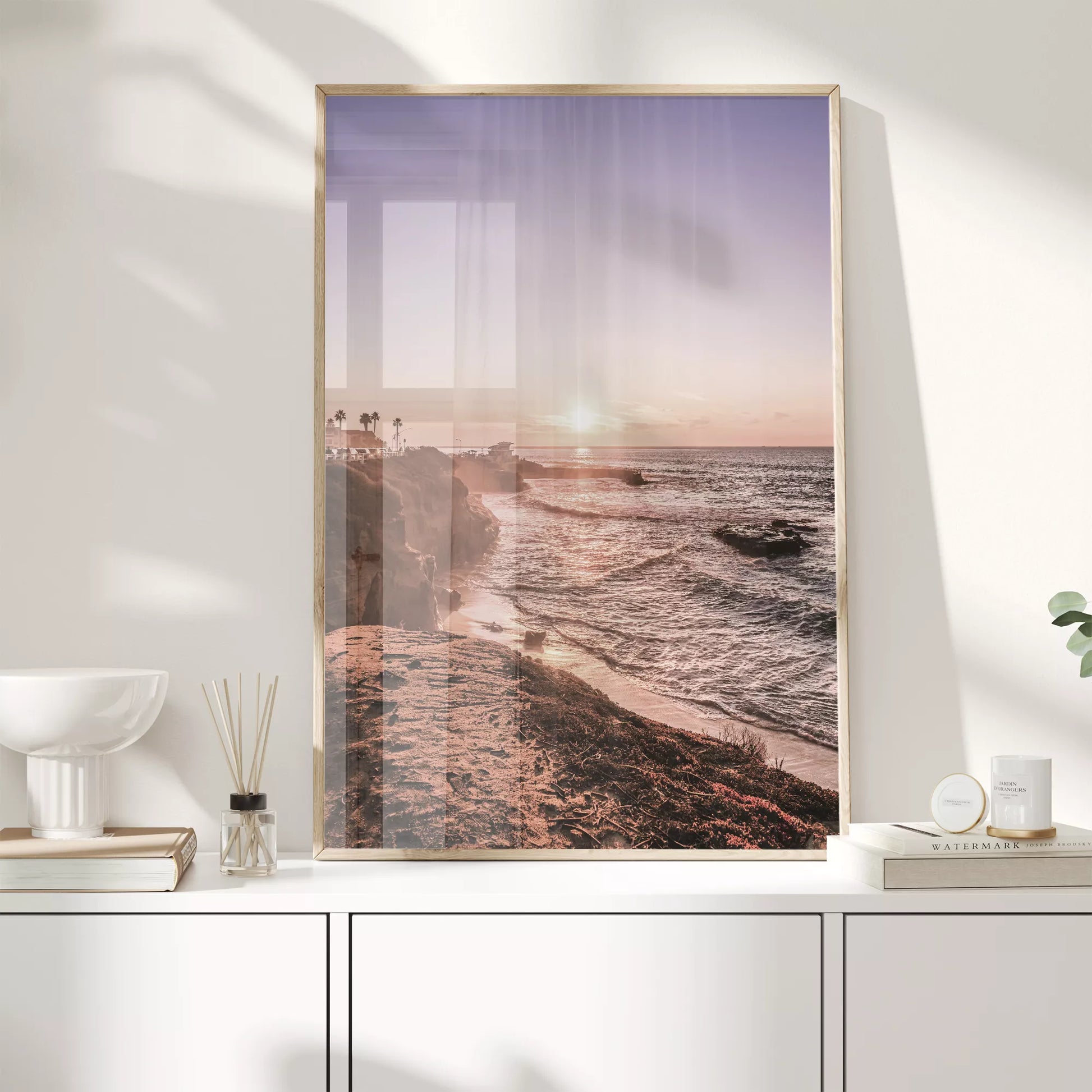 夕暮れの海岸線に沈む太陽、岩壁と波打ち際の癒しの風景