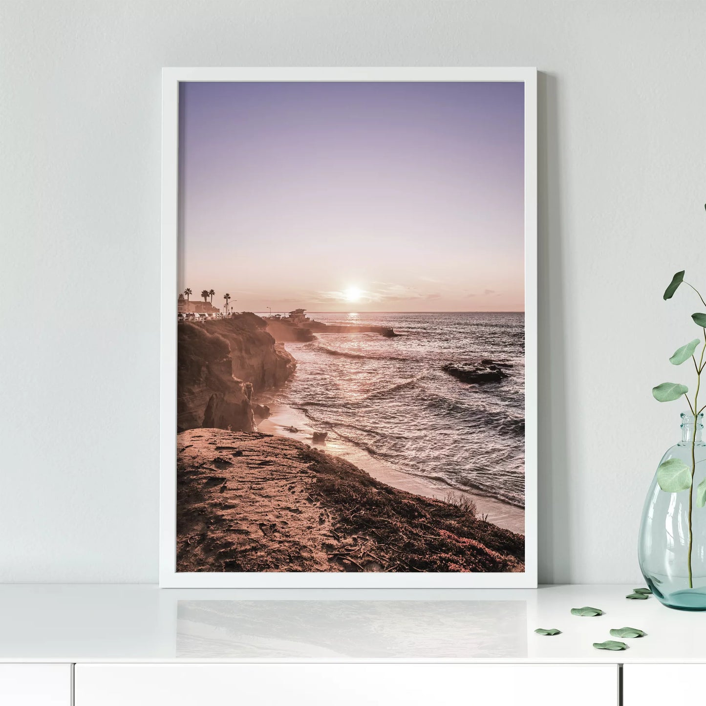 夕暮れの海岸線に沈む太陽、岩壁と波打ち際の癒しの風景