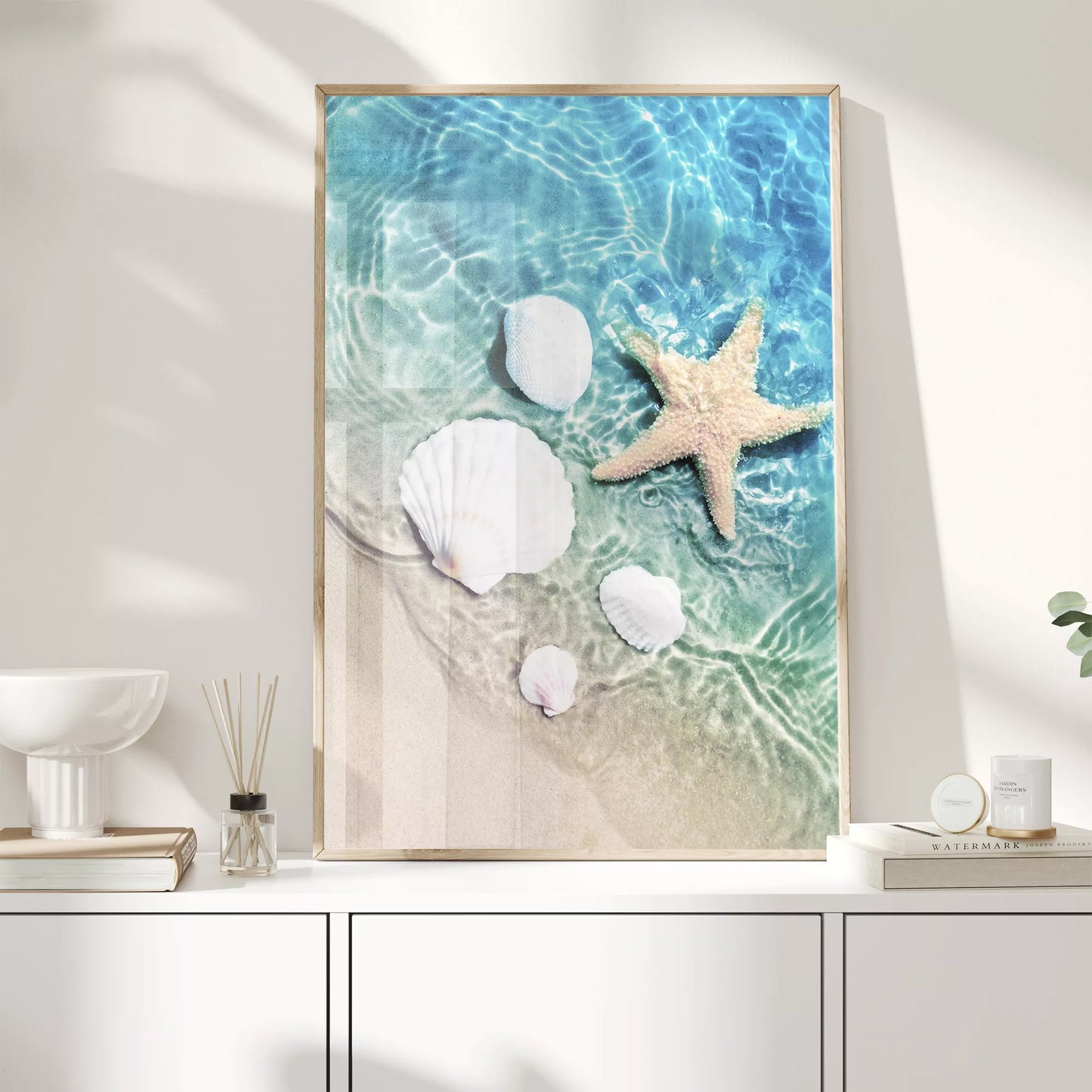 透明な青い海水とビーチに置かれた白い貝殻とヒトデのアート写真