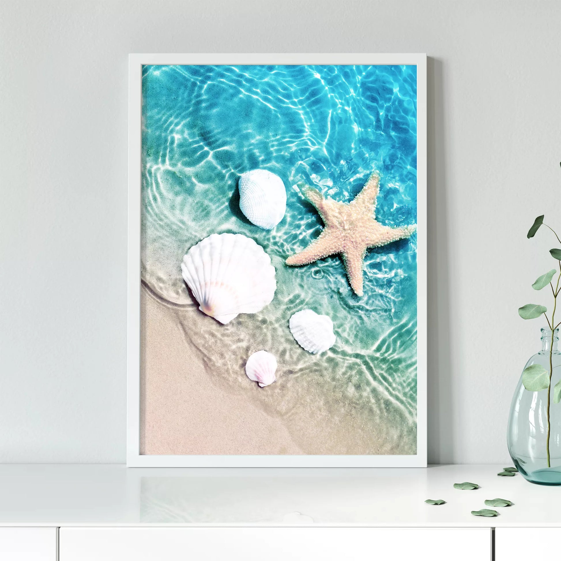 透明な青い海水とビーチに置かれた白い貝殻とヒトデのアート写真