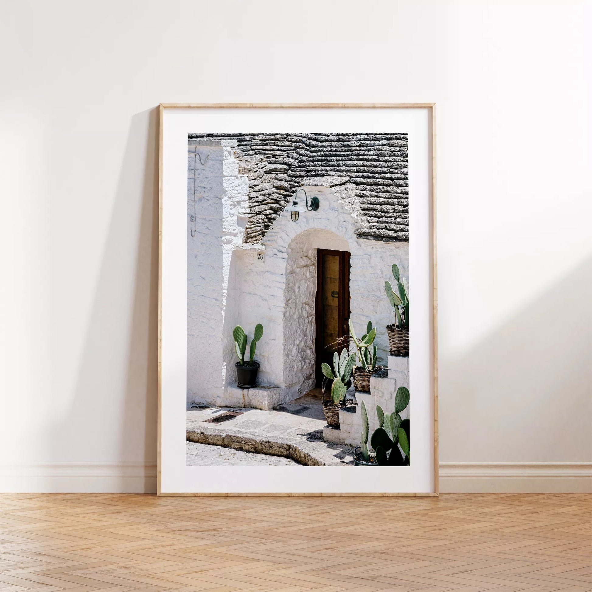 白壁の家の木製ドアとサボテンが飾られた地中海風の玄関口