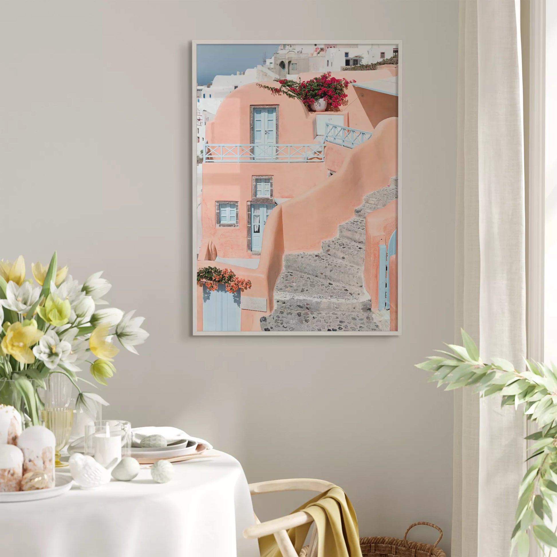 サントリーニ島のパステルピンクの建物と水色のドア、赤いブーゲンビリアが咲く地中海建築アート。白壁の街並みと石畳の小道が見える風景。