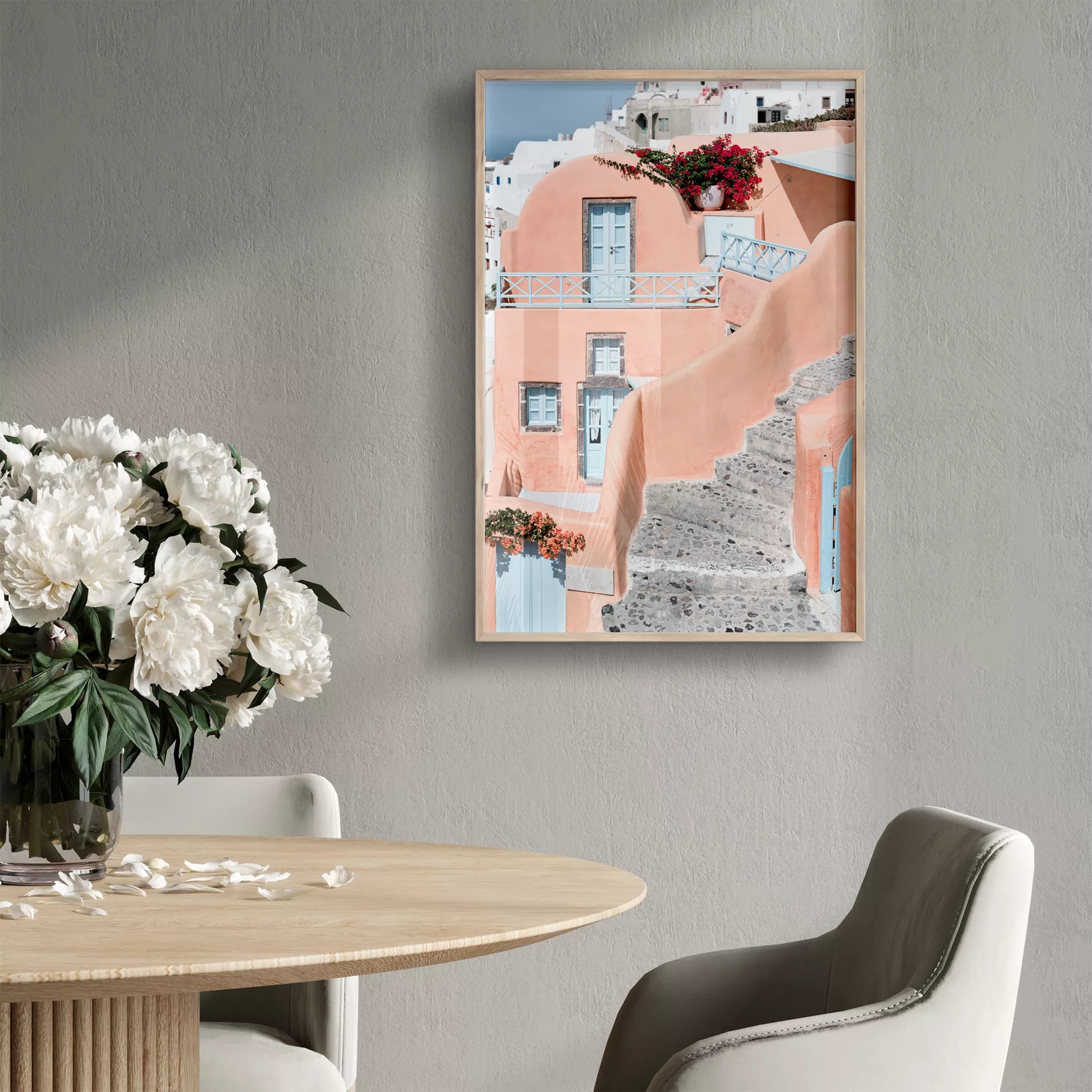 サントリーニ島のパステルピンクの建物と水色のドア、赤いブーゲンビリアが咲く地中海建築アート。白壁の街並みと石畳の小道が見える風景。