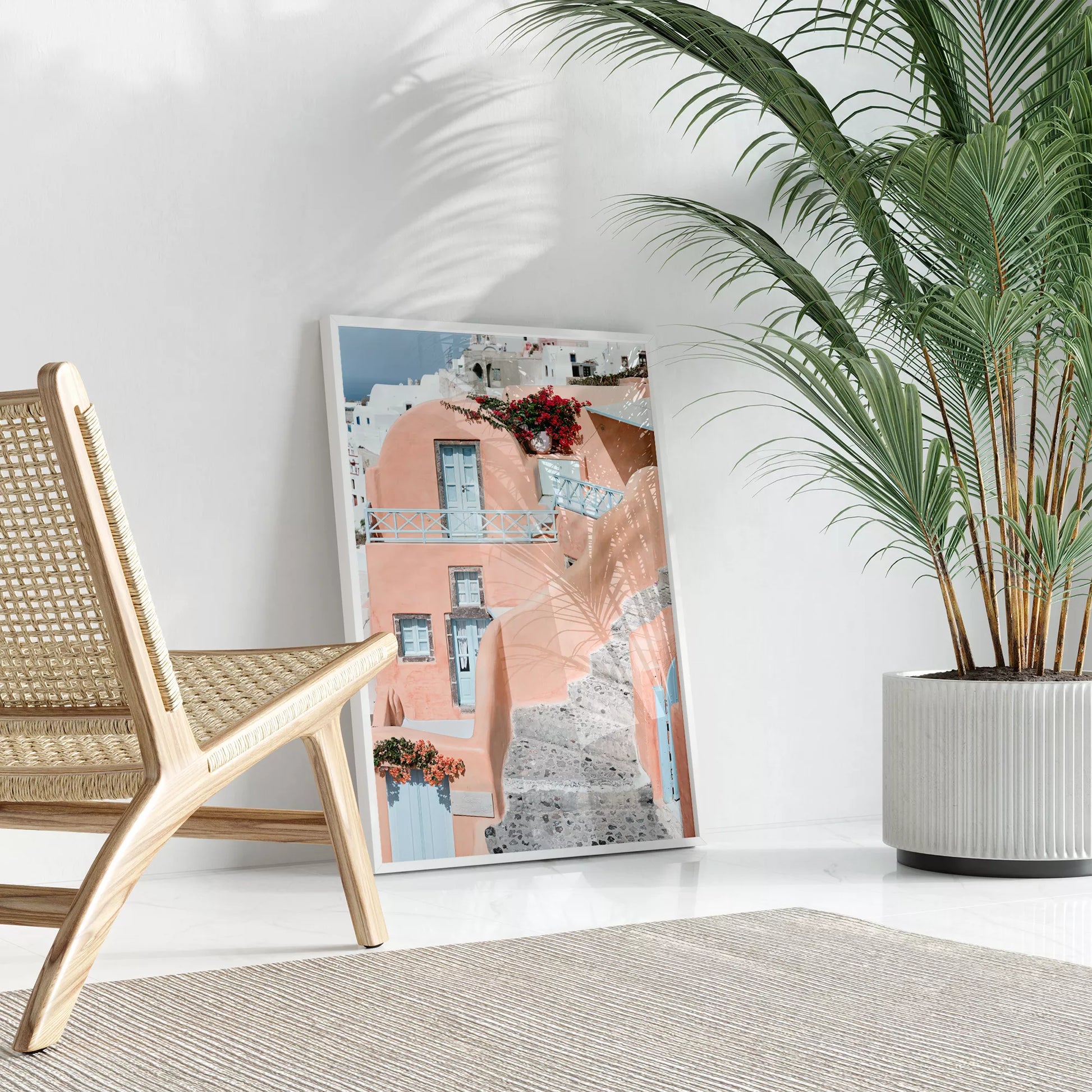 サントリーニ島のパステルピンクの建物と水色のドア、赤いブーゲンビリアが咲く地中海建築アート。白壁の街並みと石畳の小道が見える風景。