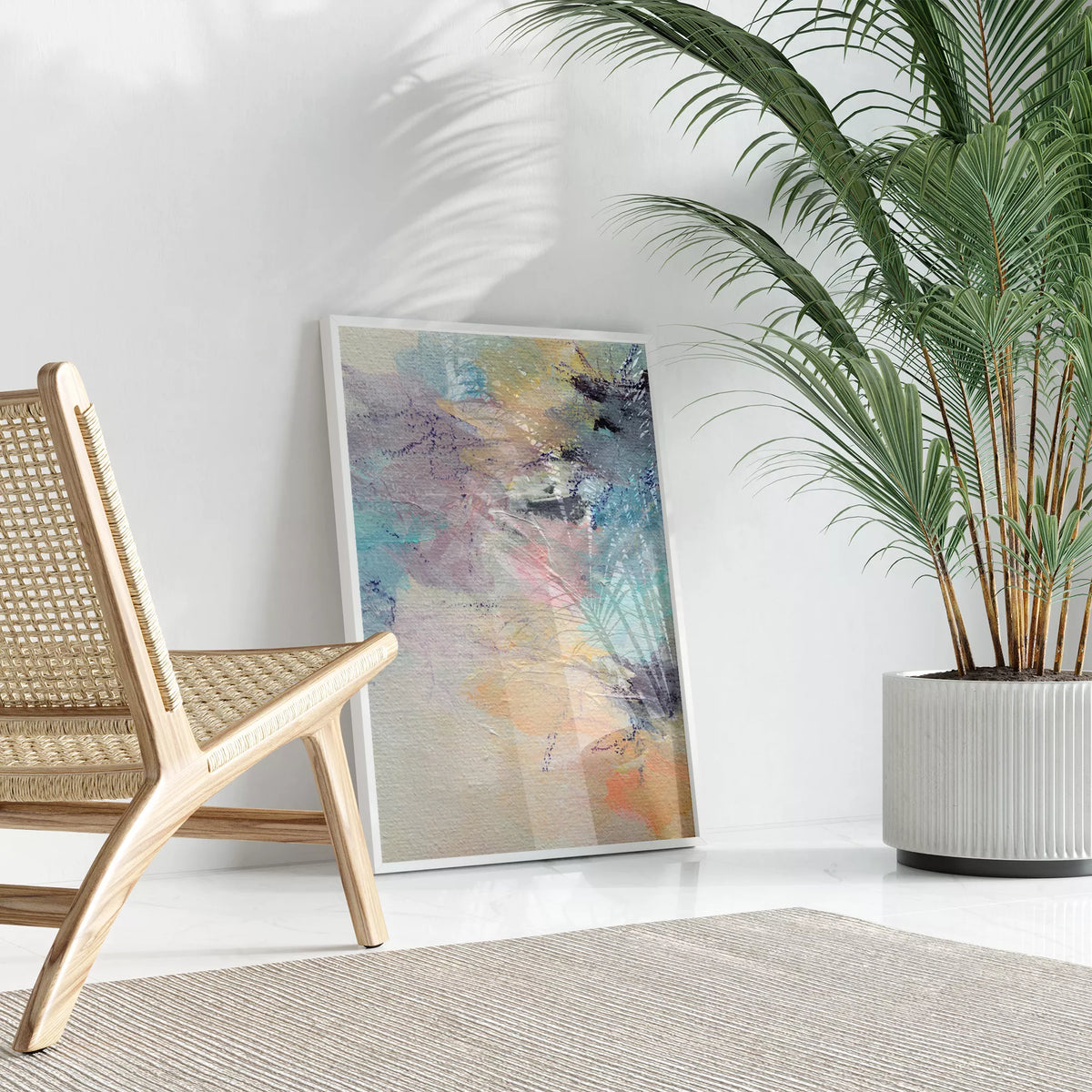 ラタンチェアと観葉植物のある明るい部屋に立て掛けたパステル抽象アートポスター