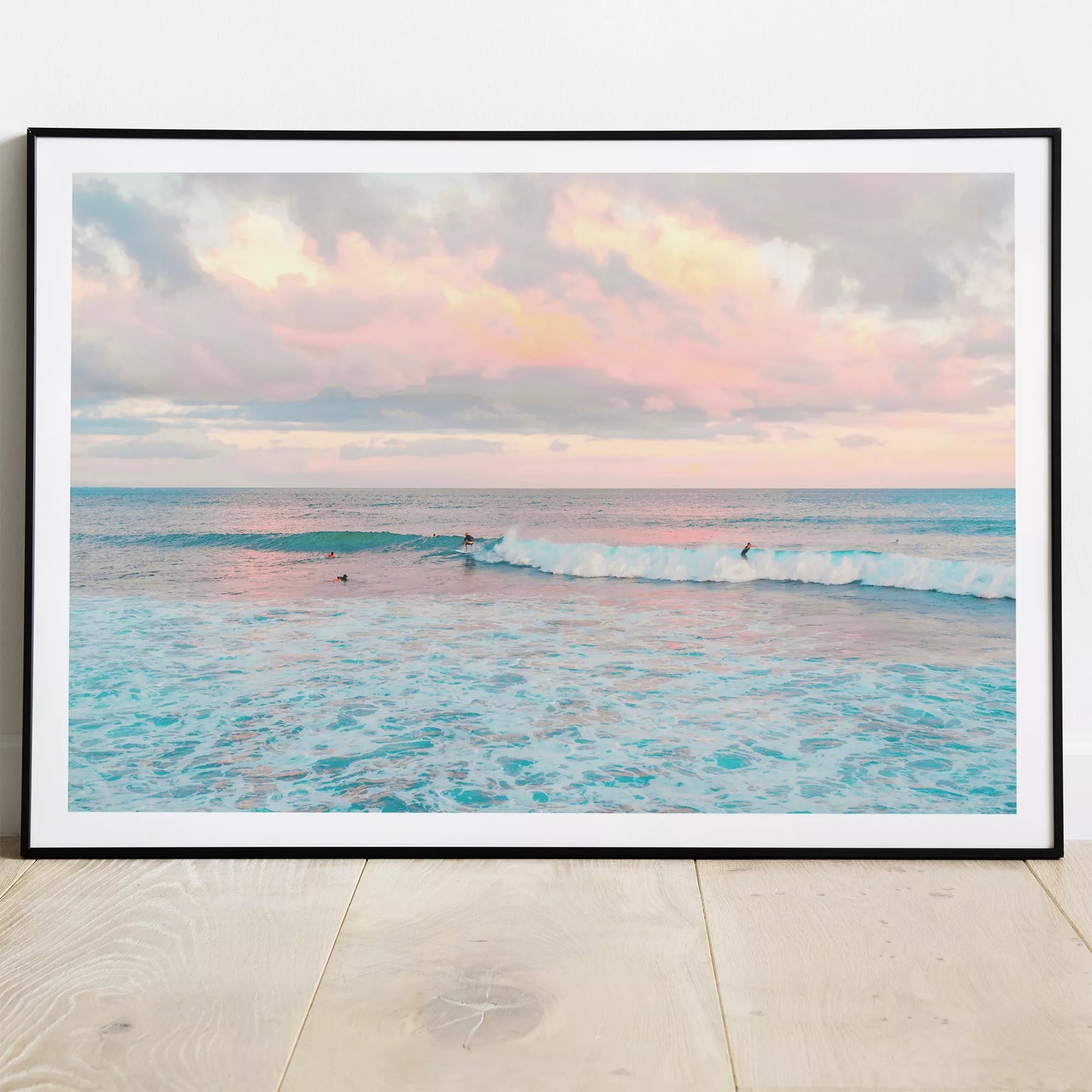 パステルピンクの夕暮れ空とターコイズブルーの波でサーフィンを楽しむ海景色