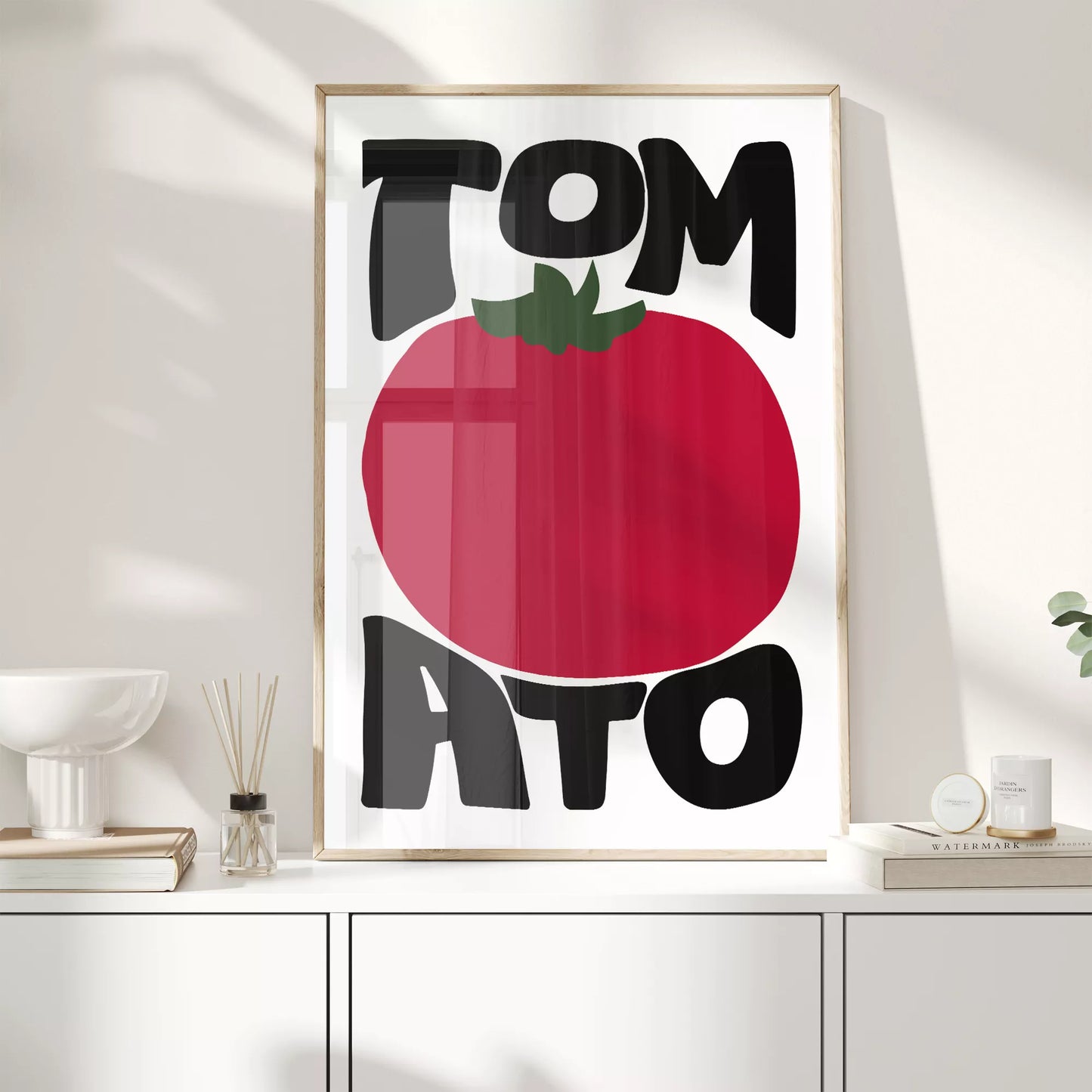 白地にモダンな黒字で「TOMATO」の文字を「TOM」と「ATO」に分け、その間に大きな赤いトマトのイラストをあしらったミニマルなアートプリント。緑の葉がアクセントとなり、シンプルながらインパクトのあるデザイン。