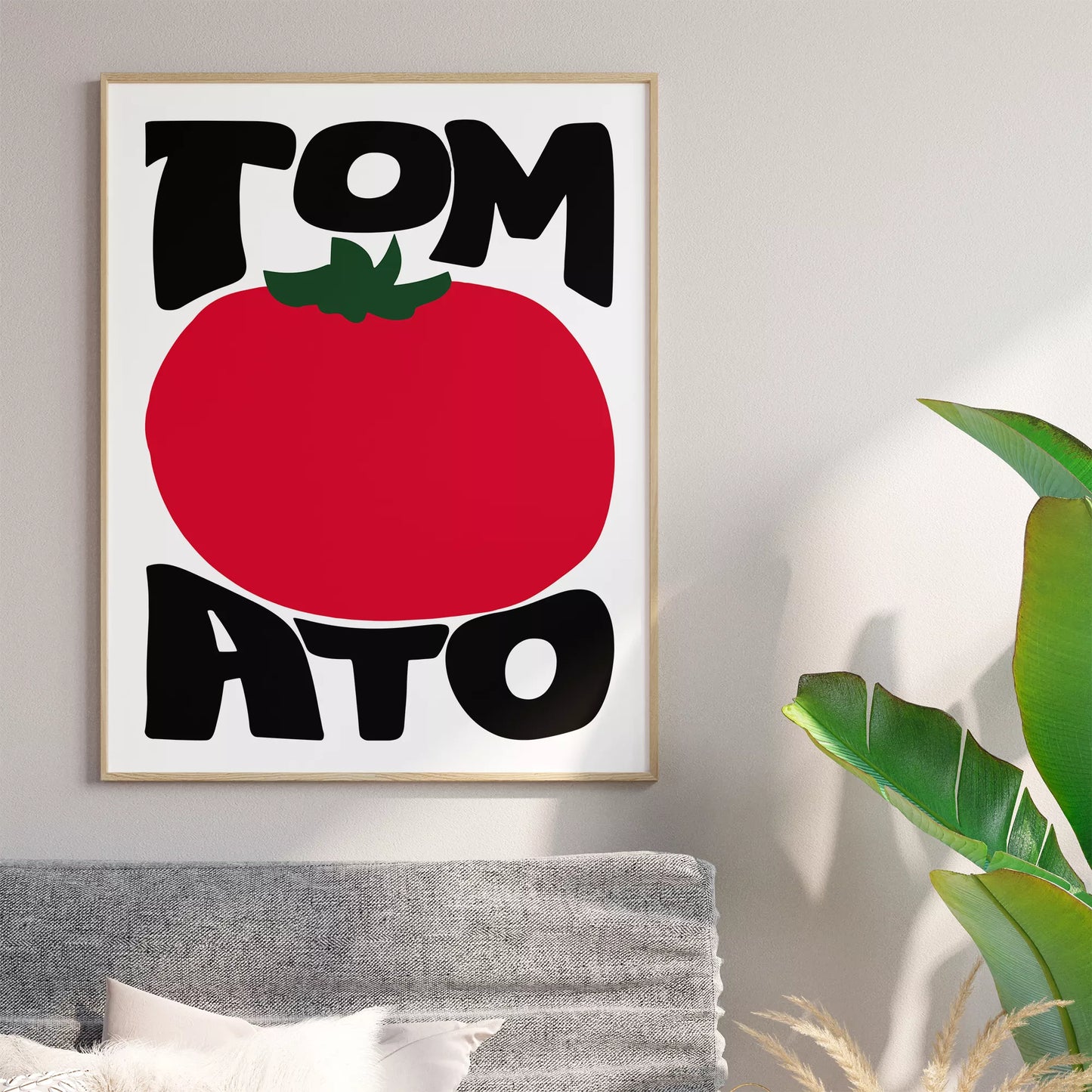白地にモダンな黒字で「TOMATO」の文字を「TOM」と「ATO」に分け、その間に大きな赤いトマトのイラストをあしらったミニマルなアートプリント。緑の葉がアクセントとなり、シンプルながらインパクトのあるデザイン。