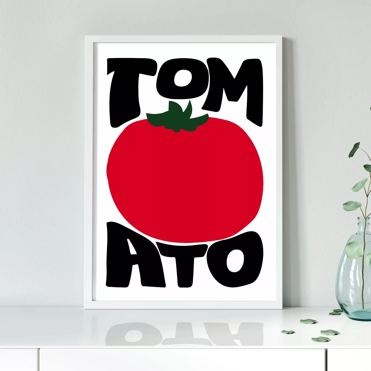 白地にモダンな黒字で「TOMATO」の文字を「TOM」と「ATO」に分け、その間に大きな赤いトマトのイラストをあしらったミニマルなアートプリント。緑の葉がアクセントとなり、シンプルながらインパクトのあるデザイン。