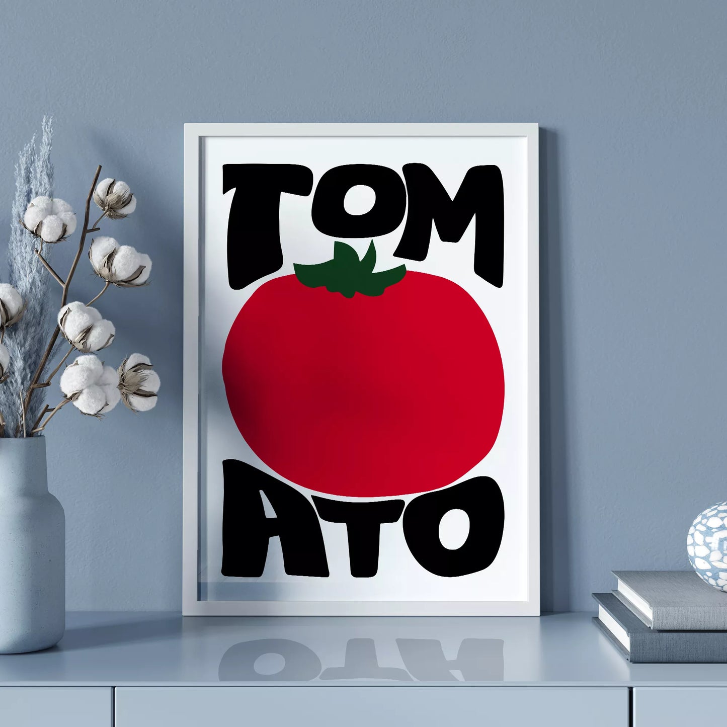 白地にモダンな黒字で「TOMATO」の文字を「TOM」と「ATO」に分け、その間に大きな赤いトマトのイラストをあしらったミニマルなアートプリント。緑の葉がアクセントとなり、シンプルながらインパクトのあるデザイン。