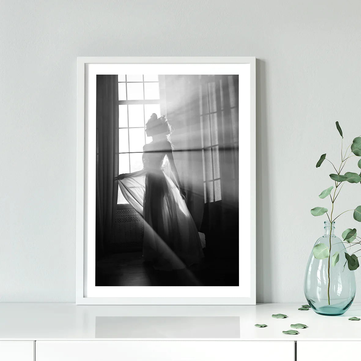 Elegant bride standing by the window, her wedding gown illuminated in the soft light