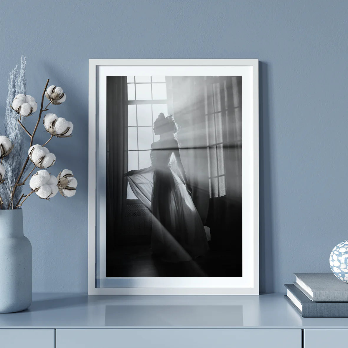 Elegant bride standing by the window, her wedding gown illuminated in the soft light