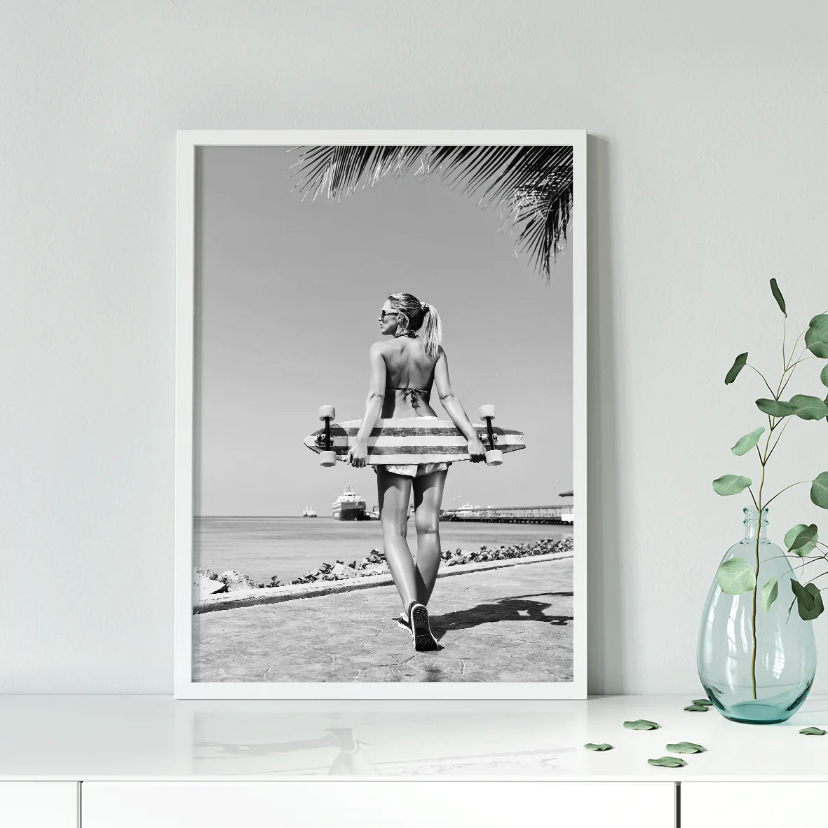 Back view of a female skater on a beach promenade with a skateboard