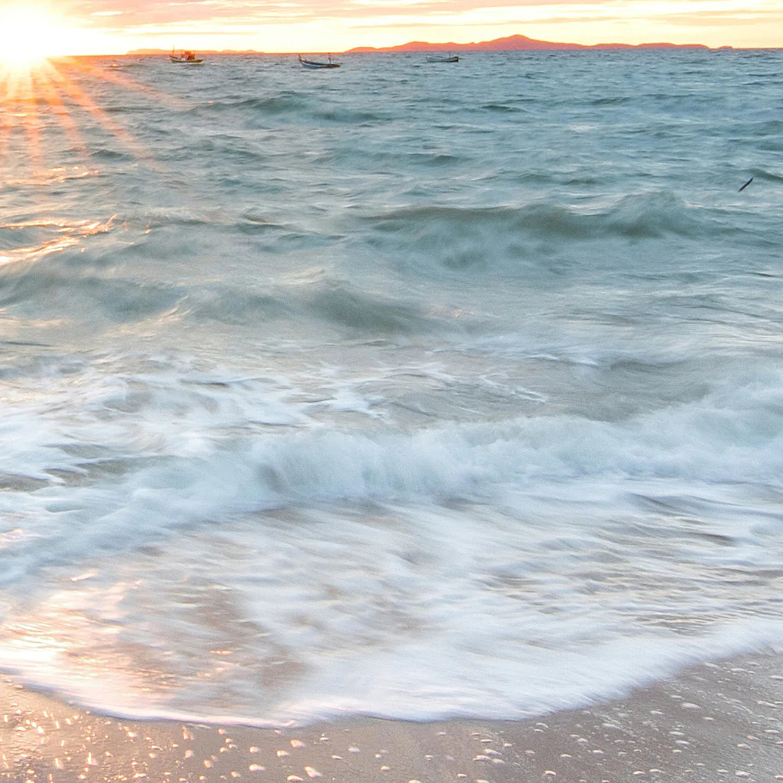 Coastal wall art of a serene sunset painting the beach sky in vibrant hues of orange and pink.