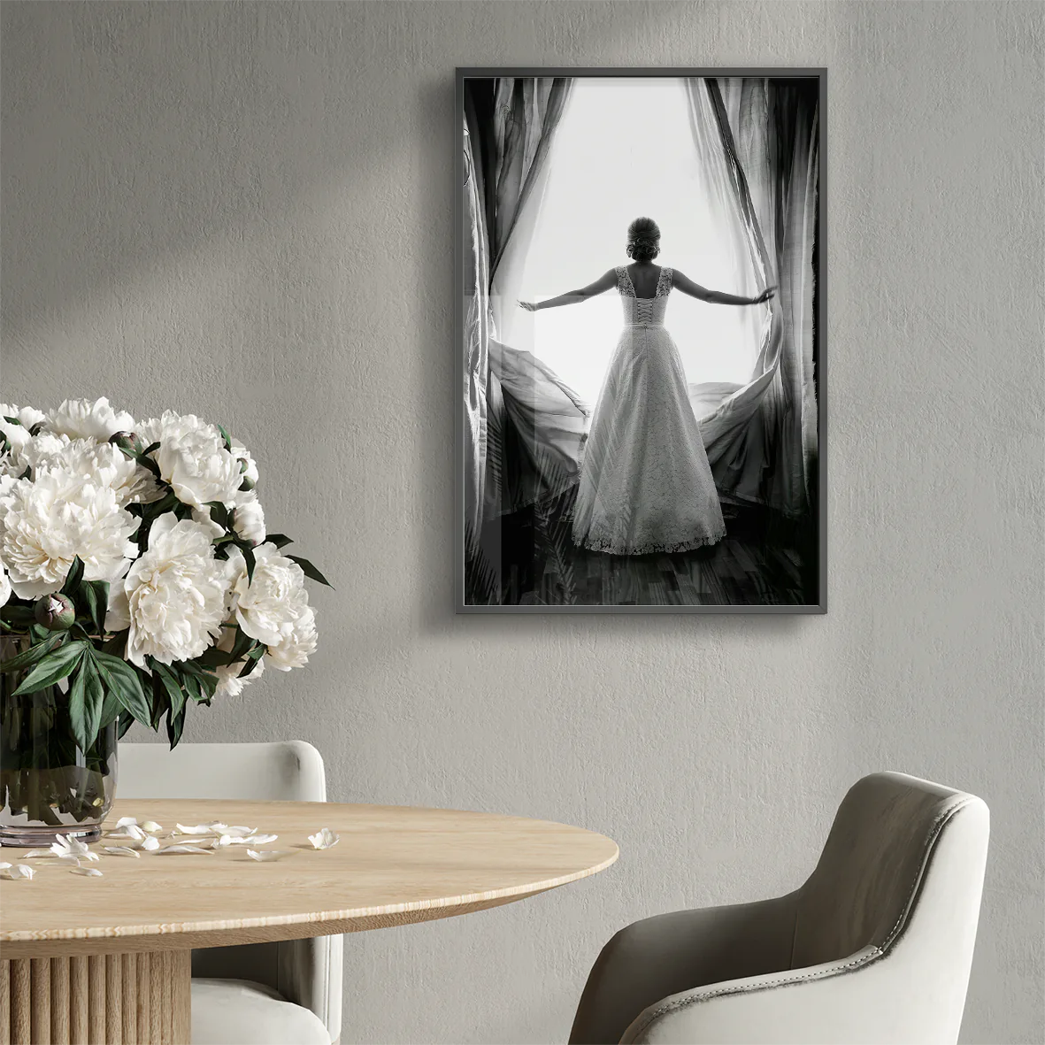 Black and white image of a bride in a lace wedding dress standing at an open window