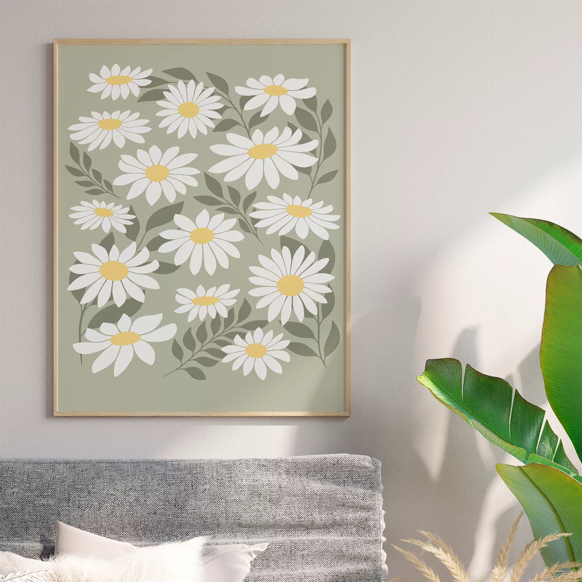 グレーのソファと観葉植物を合わせたリビングに、白いデイジーのポスターを飾ったイメージ