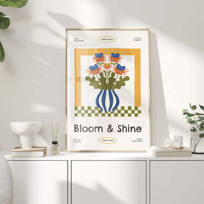 白いキャビネットの上に置いた、カラフルな花とBloom & Shineの文字入りポスター