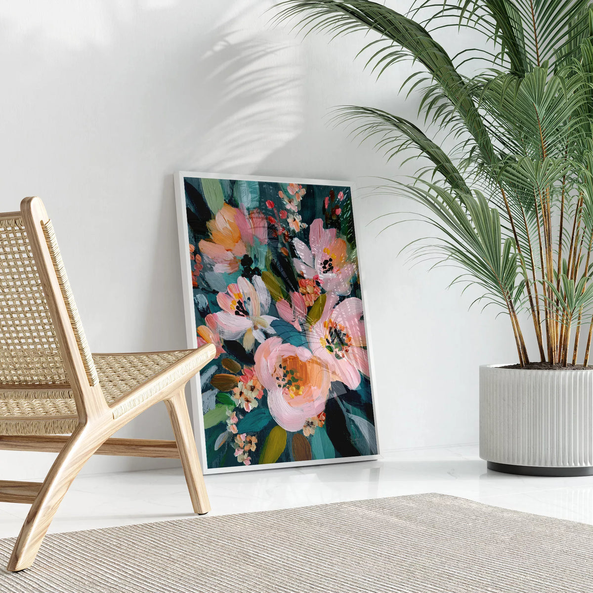 ラタンチェアと観葉植物のそばに立て掛けたピンクの花のアートポスター