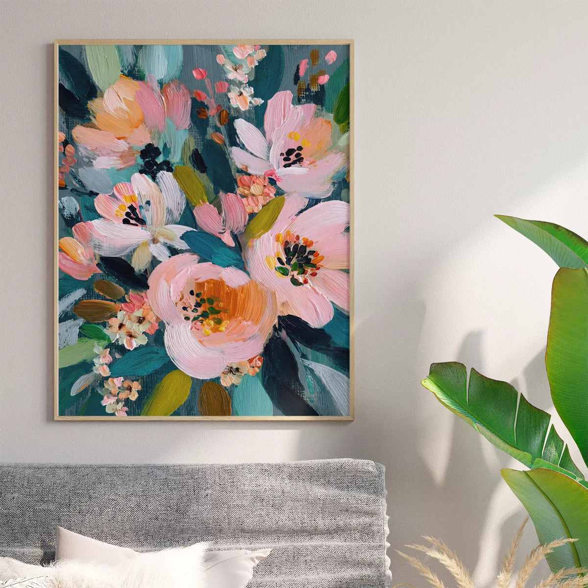 グレーのソファ上の壁に飾ったピンクの花とティールの葉のアートポスター