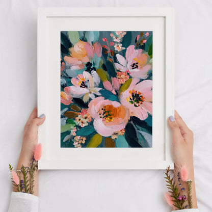 白フレームに入れたピンクの花のアートポスターを手に持った展示例