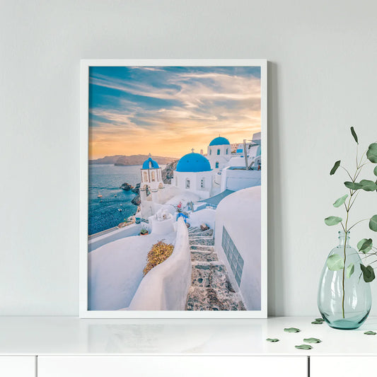 Wall art capturing the beauty of Santorini's sunset with blue domes and whitewashed buildings against a pastel sky