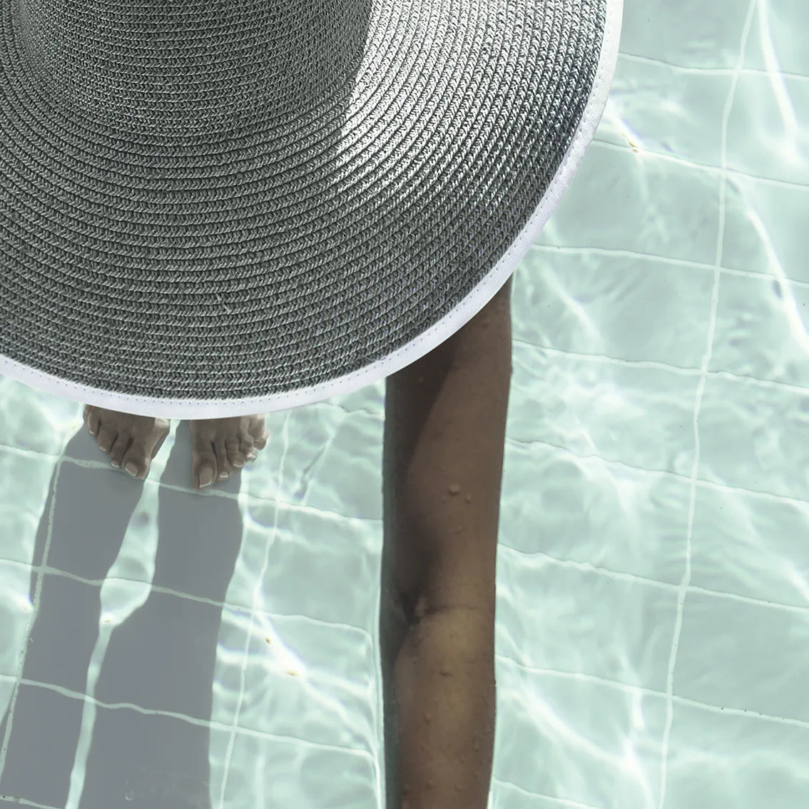 Elegant wall art showcasing a tranquil pool scene with a sunhat-clad figure,