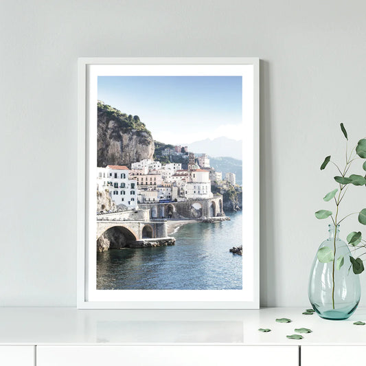 Wall art of a Mediterranean coastal town with historic white buildings and sea arches in daylight