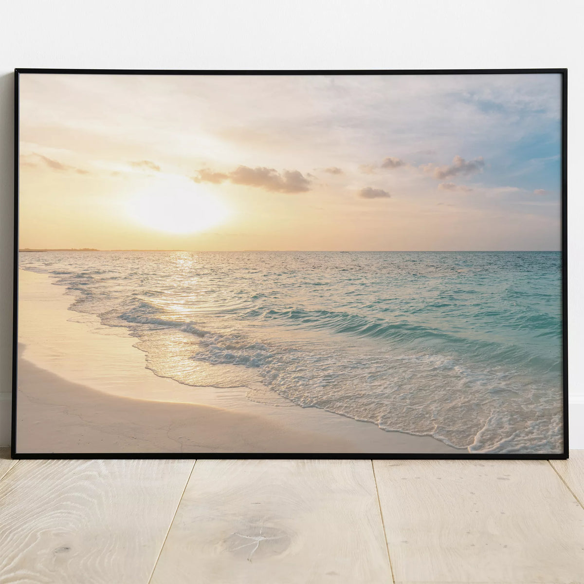 砂浜に寄せる白い波と水平線の夕日を表したポスターの黒いフレームでの展示イメージ