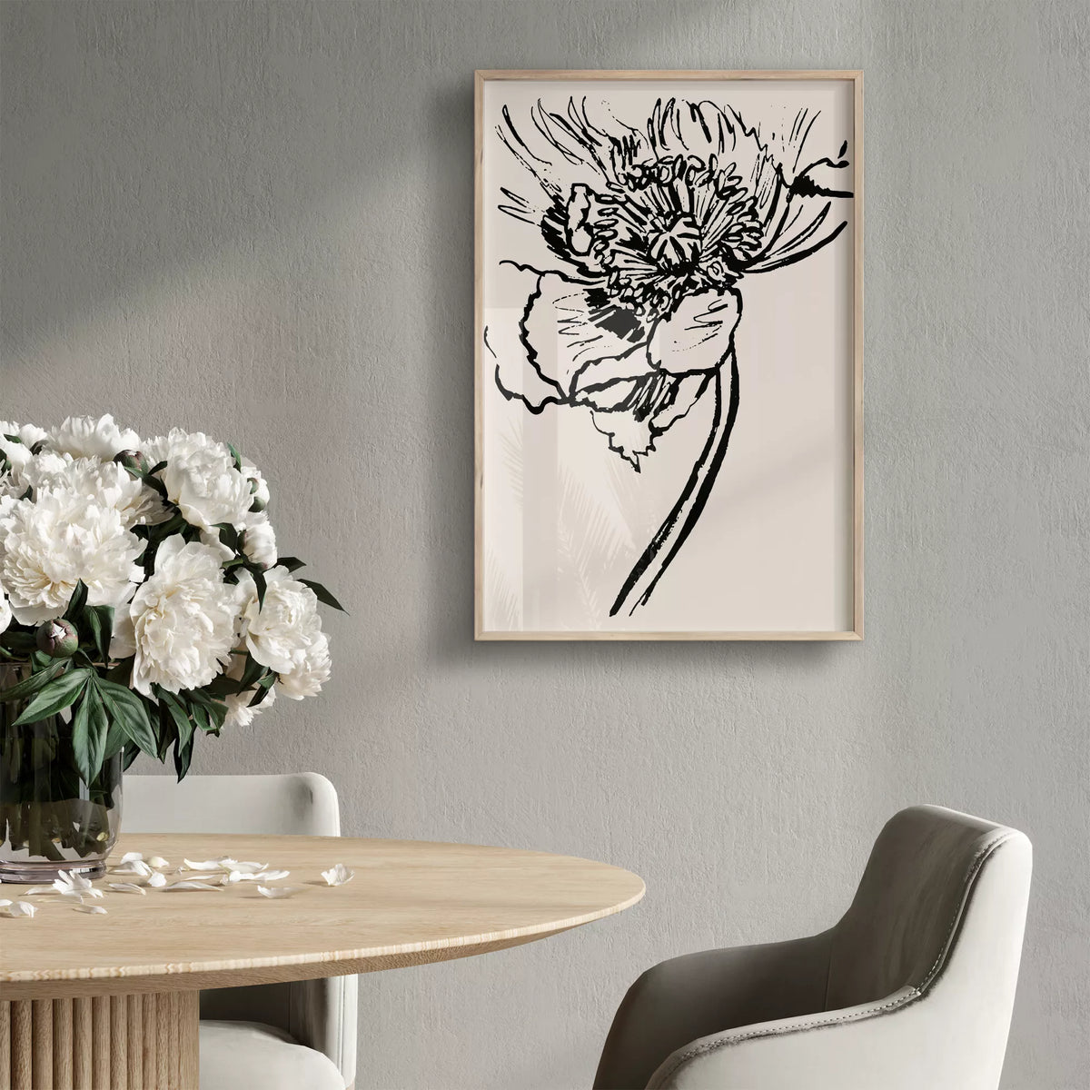ベージュの背景に黒線で描いた大輪の花のポスターを、花を飾った丸いダイニングテーブルのそばに掛けたイメージ