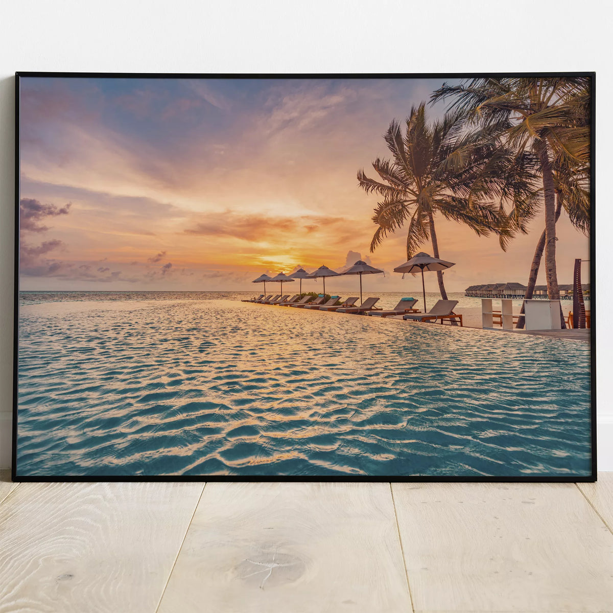 白い壁と木の床に立てかけた、ヤシの木と夕日が水面に映るリゾートプールのアートポスター